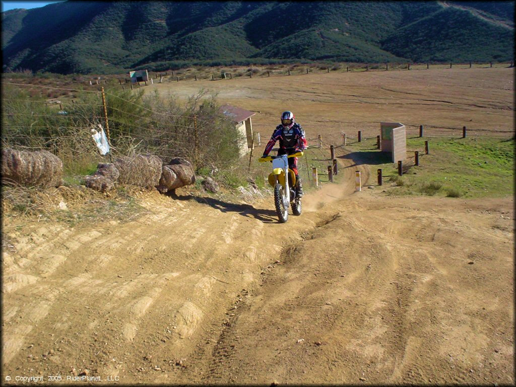 Man on Suzuki RM-250 going up trail from staging area.