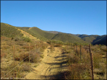 ATV trail surrounded by metal posts and fencing.