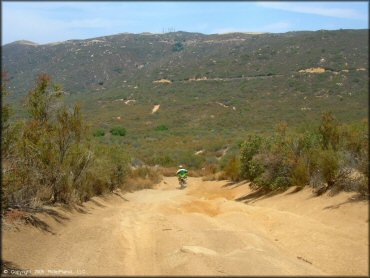 Man on CRF150F riding down 4x4 trail.