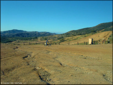 Woman on RM-250 dirt bike riding around staging area.