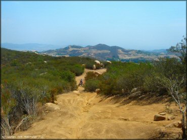 Scenic view of ATV trail with rolling hills and mountains in the background.