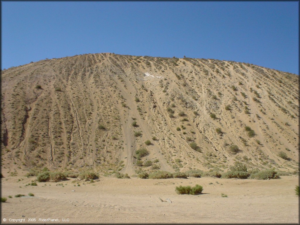 A photo taken at the base of a steep and sandy hill climb.