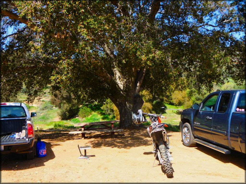 KTM MX motorcycle on kickstand parked between two trucks.