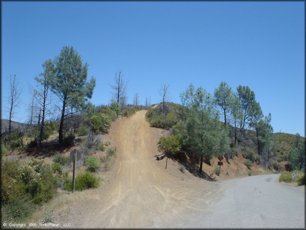 Stop sign at intersection of trail and paved road.