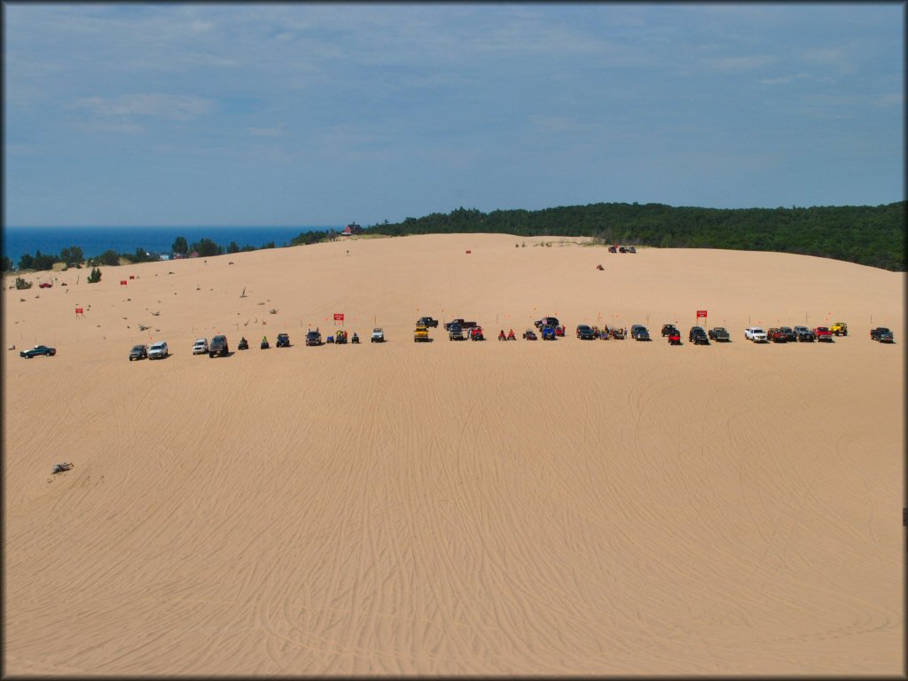 Scenic view of group of 4x4s, ATVs and UTVs at Silver Lake Sand Dunes with Lake Michigan in the background.